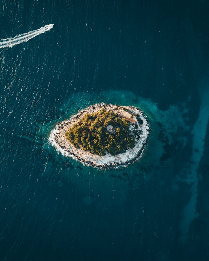 Aerial view of a small green island surrounded by deep blue sea